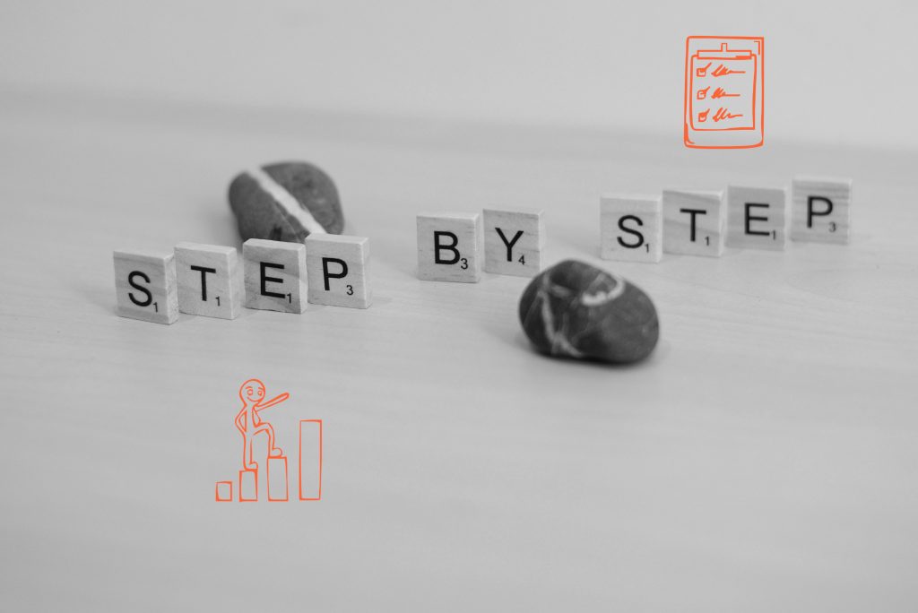 Buchstaben auf Holz mit der Aufschrift Step by Step